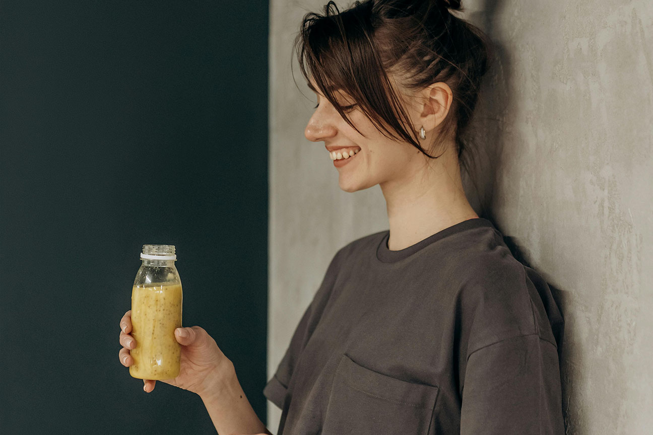 Mujer bebiendo un batido de frutos amarillos
