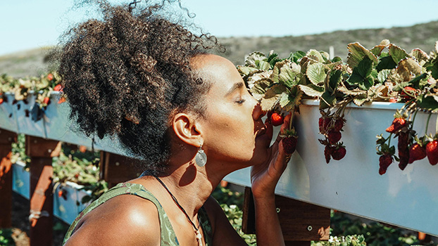 Fotografía de una mujer oliendo unas frutas